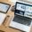 Open Design AI. A designer's workspace with a laptop displaying website designs, a tablet with wireframes, and a notebook of sketches